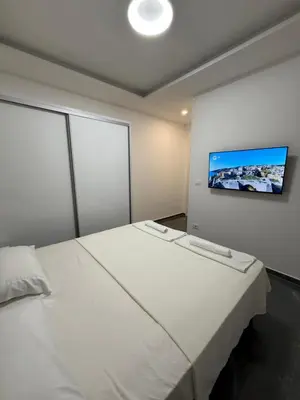a bedroom with a white bed and a flat screen tv at Skyline View Apartment in Ulcinj