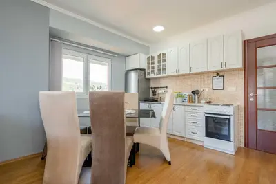 a kitchen with white cabinets and a table and chairs at Azzurro Apartment in Utjeha in Utjeha