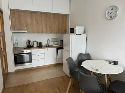 a kitchen with a white refrigerator and a table and chairs at Pretty apartment near the sea! in Budva