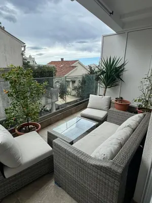 a balcony with wicker chairs and a glass table at Pretty apartment near the sea! in Budva