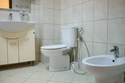 a white bathroom with a toilet and a sink at SOHO CITY Grunevs apartments 2 in Bar