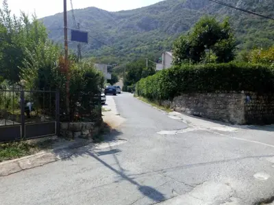 an empty street with a car parked on the road at Nina Apartment in Škaljari