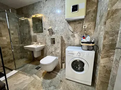 a bathroom with a washing machine and a sink at Salt & Stone Apartment in Sveti Stefan