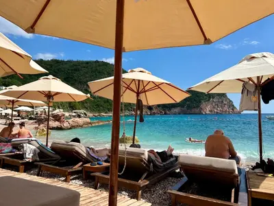a group of people laying on a beach with umbrellas at Salt & Stone Apartment in Sveti Stefan