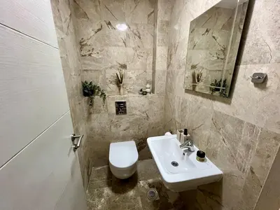 a bathroom with a white toilet and a sink at Salt & Stone Apartment in Sveti Stefan