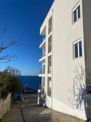 a white building with the ocean in the background at Biser mora in Dobra Voda