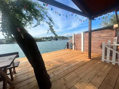 a wooden deck with a tree on the water at Suncica Ada Bojana in Ada