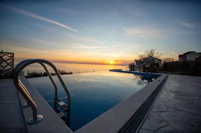 a swimming pool with a sunset in the background at Villa Aurora Azure - Luxury Infinity Pool Resort in Katun