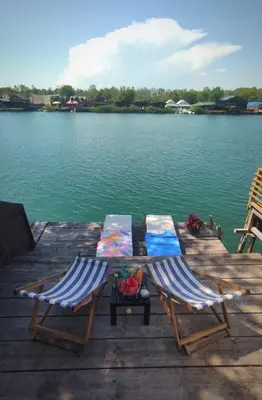 two chairs sitting on a dock next to the water at Zvoncica, Ada Bojana in Ada