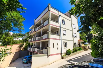 an apartment building with a car parked in front of it at Yu&li Rose Apartments Adriatic in Bar