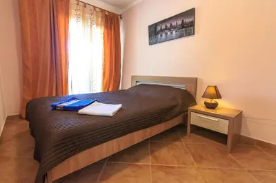a bedroom with a bed and a table with a lamp at Yu&li Rose Apartments Adriatic in Bar