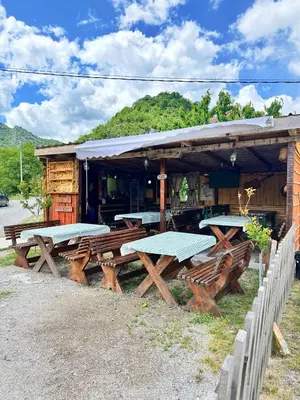 a group of picnic tables in front of a building at Camp River in Virpazar