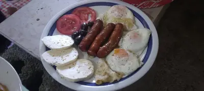 a plate of breakfast food with eggs sausage and tomatoes at Camp River in Virpazar