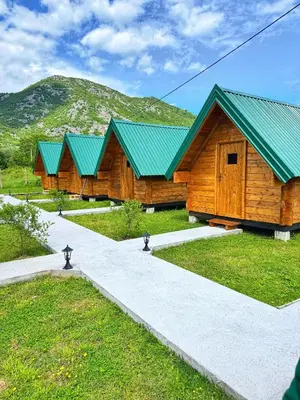a row of wooden buildings with green roofs at Camp River in Virpazar