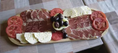 a plate of meats and cheese and tomatoes on a table at Camp River in Virpazar
