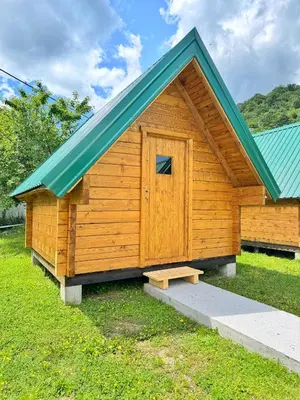 a wooden cabin with a blue roof and a door at Camp River in Virpazar