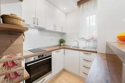 a white kitchen with white cabinets and a sink at Aurora Apartment 1 with Parking in Budva