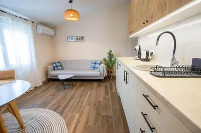 a kitchen and a living room with a couch at Bright & Cozy Apartment in quiet area near Airport in Golubovci