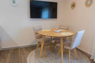 a dining room table with three chairs and a television at Bright & Cozy Apartment in quiet area near Airport in Golubovci