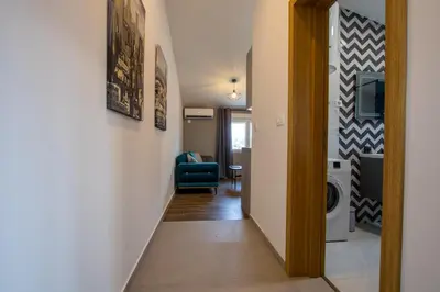 a hallway leading to a living room with a blue chair at Modern apartment in a quiet area near the Airport in Golubovci