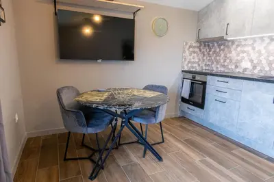 a kitchen with a table and two chairs and a tv at Modern apartment in a quiet area near the Airport in Golubovci
