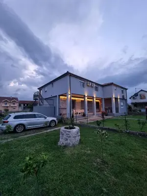 a house with a car parked in a yard at Modern apartment in a quiet area near the Airport in Golubovci
