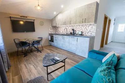a living room with a blue couch and a kitchen at Modern apartment in a quiet area near the Airport in Golubovci