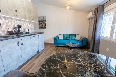 a kitchen and a living room with a blue couch at Modern apartment in a quiet area near the Airport in Golubovci