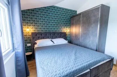 a bedroom with a blue bed with a padded headboard at Modern apartment in a quiet area near the Airport in Golubovci