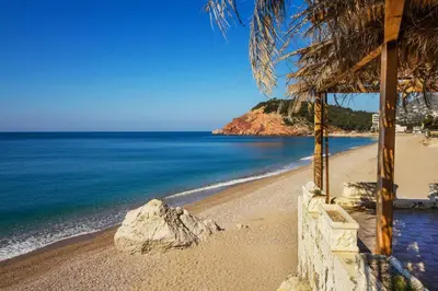 a beach with a large rock and the ocean at Urban apartments Sutomore in Sutomore