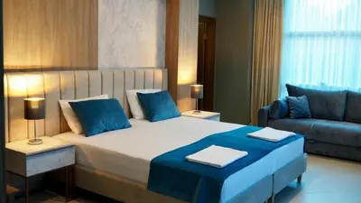 a bedroom with a bed with blue pillows and a couch at Urban apartments Sutomore in Sutomore