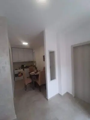 a living room with a table and chairs and a kitchen at Apartman Šušanj 2 in Bar