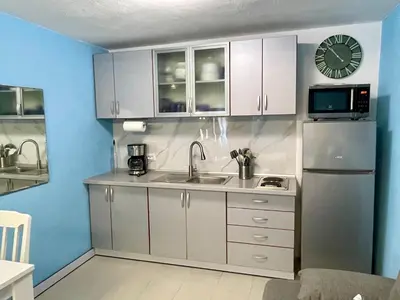a kitchen with white cabinets and a sink and a refrigerator at Sutomore Panorama Studio in Sutomore