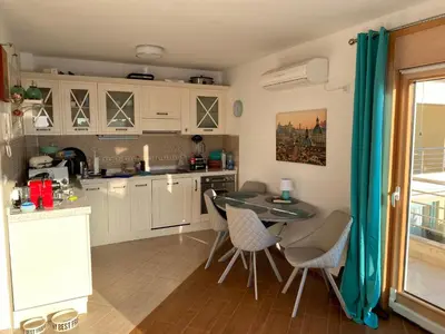 a kitchen with white cabinets and a table and chairs at Villa Nova Premium Apartment No 7 in Petrovac na Moru