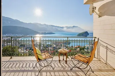 a patio with two chairs and a table on a balcony at Villa Sofiia with panoramic views of the old town in Budva