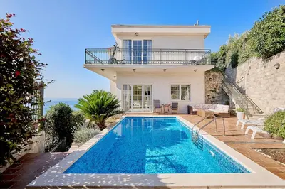 a villa with a swimming pool in front of a house at Villa Sofiia with panoramic views of the old town in Budva