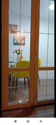 a room with a table and a yellow chair through a glass door at Stan Rafailovici LM in Rafailovici