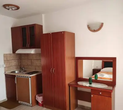 a small kitchen with wooden cabinets and a bed at Mediterano Apartments in Ulcinj