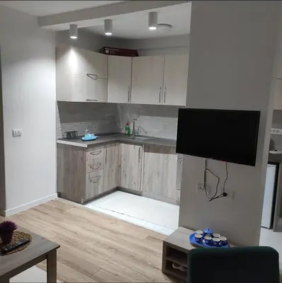 a kitchen with wooden cabinets and a flat screen tv at Mediterano Apartments in Ulcinj