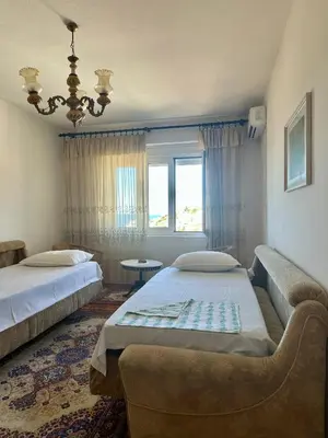 a bedroom with two beds and a couch and a window at Nimanbegu Apartments in Ulcinj