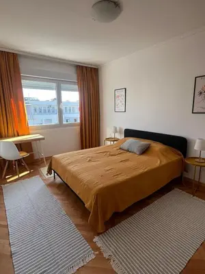 a bedroom with a bed and a table and a window at Cozy & Sunny 2-bedroom in best location in the city in Podgorica