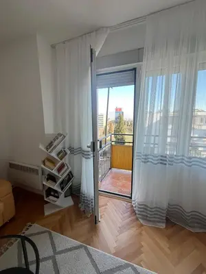 a room with a sliding glass door with a balcony at Cozy & Sunny 2-bedroom in best location in the city in Podgorica