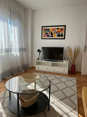 a living room with a tv and a table at Cozy & Sunny 2-bedroom in best location in the city in Podgorica