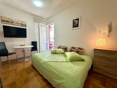a bedroom with a bed with a television and a table at Happy Time Studio in Petrovac na Moru