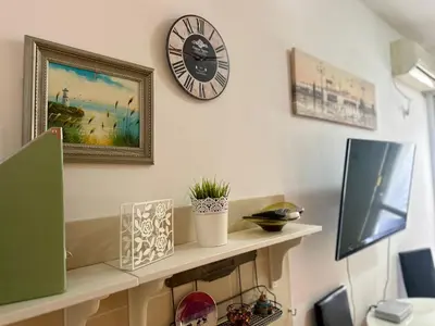a clock on a wall above a shelf with a tv at Happy Time Studio in Petrovac na Moru