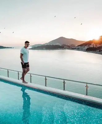a man standing on the edge of a swimming pool at Hotel Ponta Nova in Budva