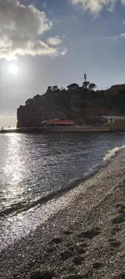 a beach with the sun shining on the water at Kolovic Susanj in Bar