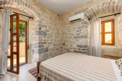 a bedroom with a bed and a stone wall at Historic Waterfront House in Muo