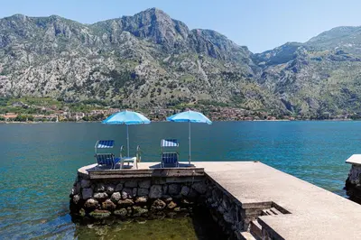 two chairs and two umbrellas on a dock in the water at Historic Waterfront House in Muo