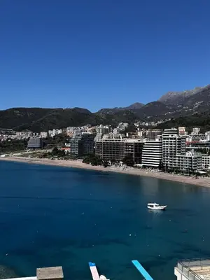 a boat in the water in front of a beach at Apartament Rafailovici Budva in Budva